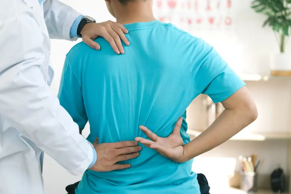 A doctor examining a patient's back and spine.