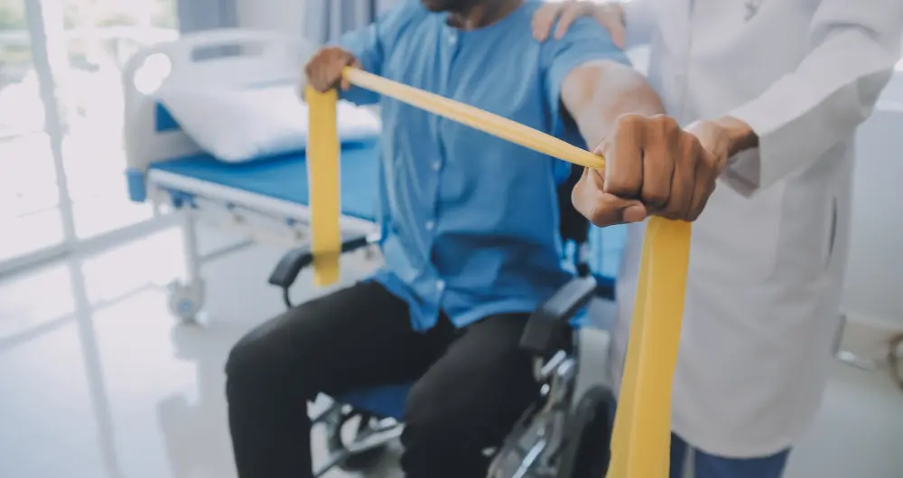 A patient in a wheelchair using resistance bands with help.