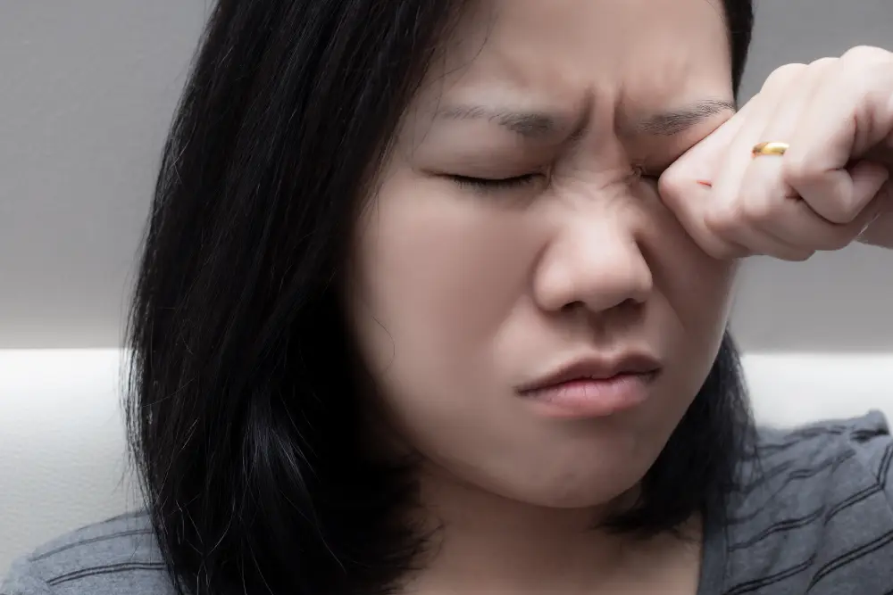 A woman rubbing her closed eye with her fist.